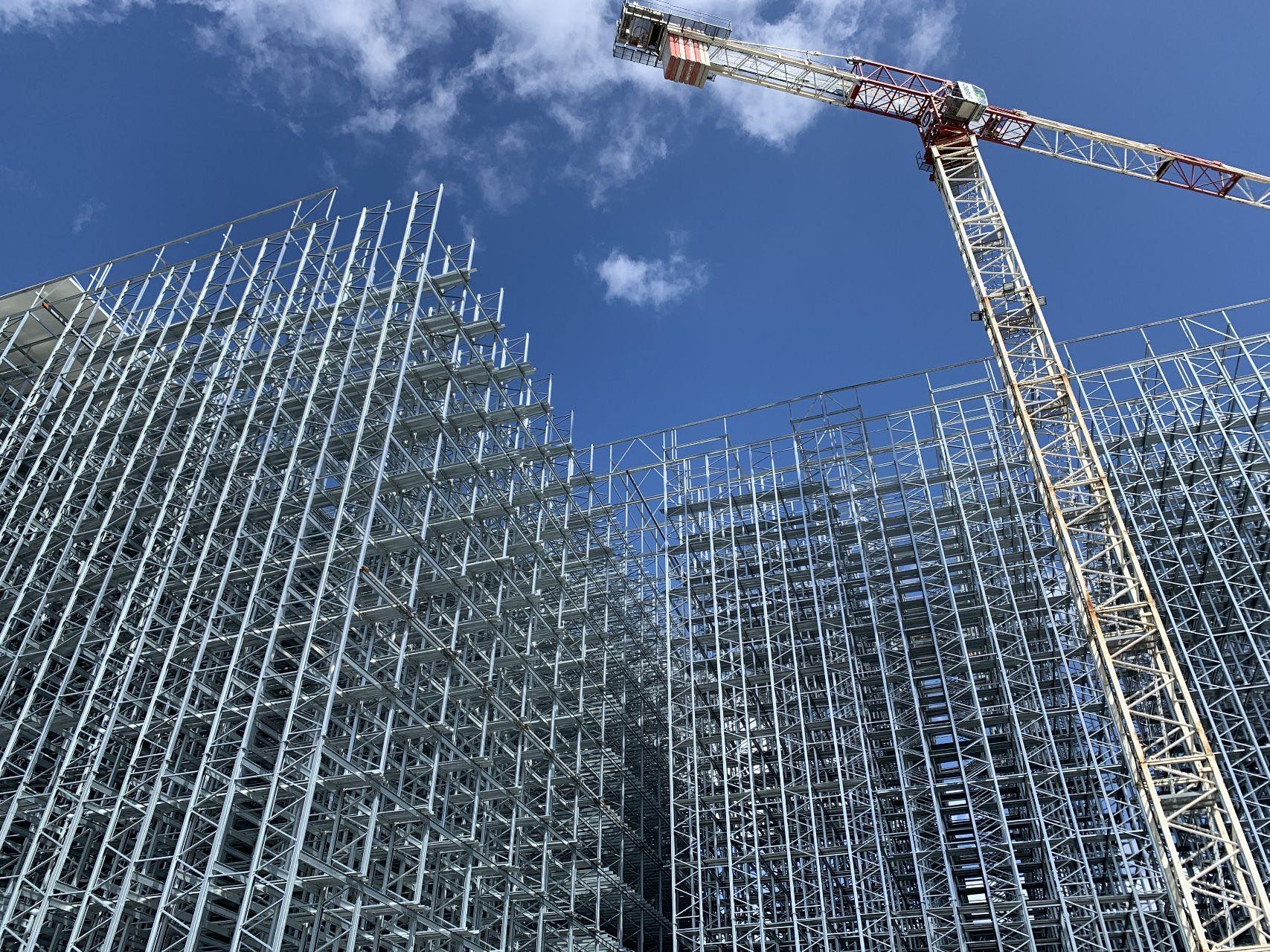 Steel racking rising against the sky on a cold storage project, with a tower crane overhead